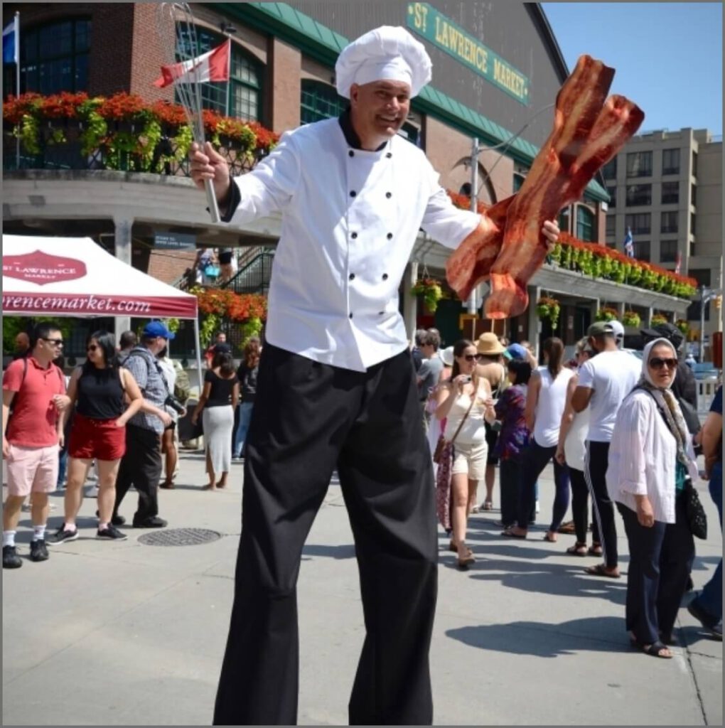 A man on stilts wearing a chef hat