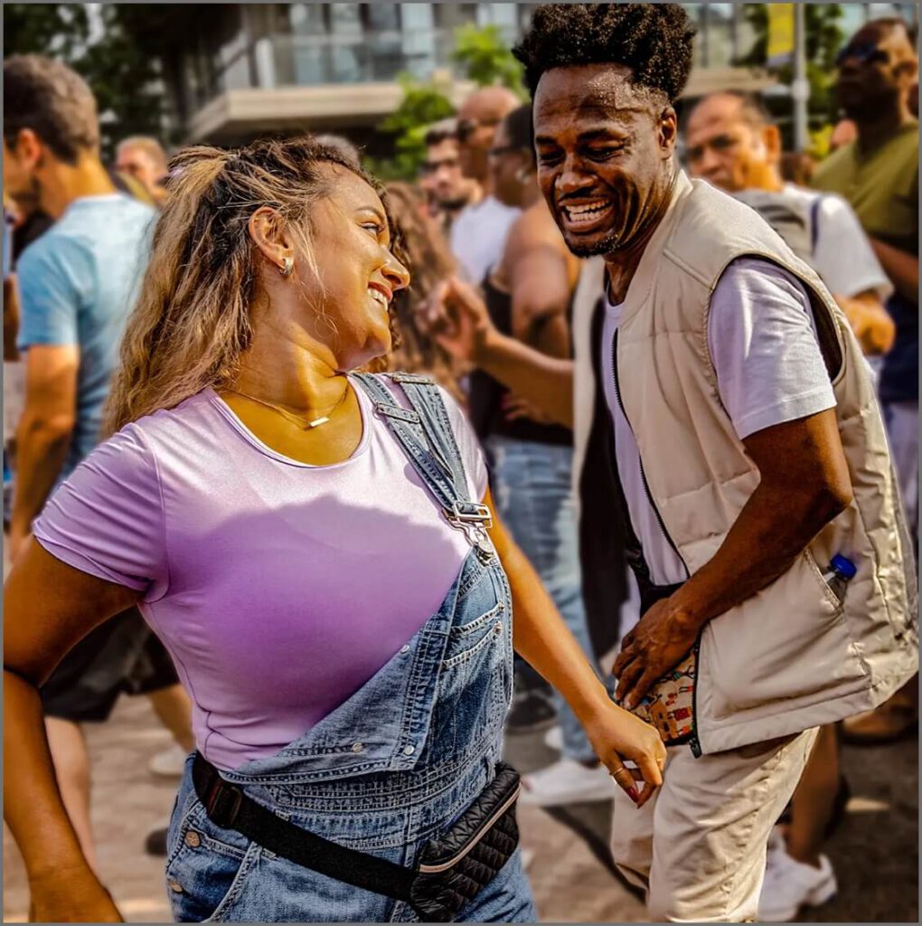 A man and a woman dance salsa on Market Street